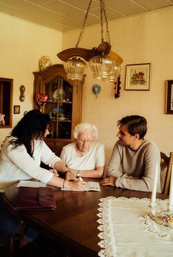 Junge Frau hilft älteren Dame beim Ausfüllen von Unterlagen