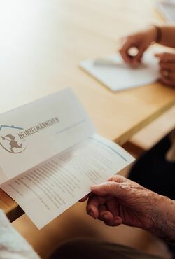 Heinzelmännchen Seniorenbetreuung Flyer ältere Dame hält Flyer in der Hand