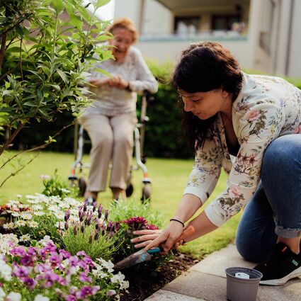 Seniorenbetreuerin pflegt Pflanzen im Garten