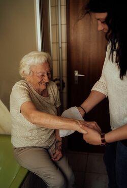 Seniorenbetreuer wäscht Seniorin den Arm