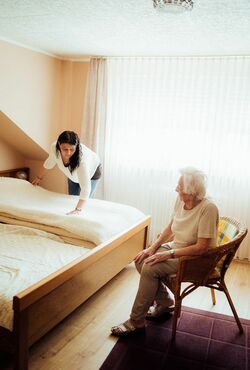 Seniorenbetreuerin bezieht Bett der Seniorin neu