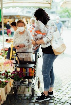 Junge Frau geht mit älterer Dame Einkaufen