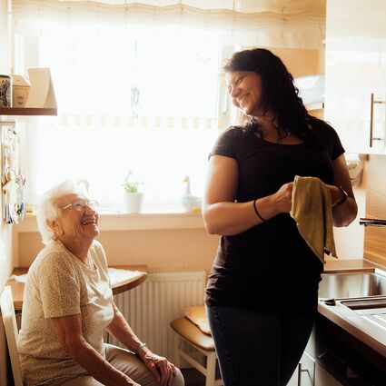 Junge Dame hilft älteren Dame beim Spühlen